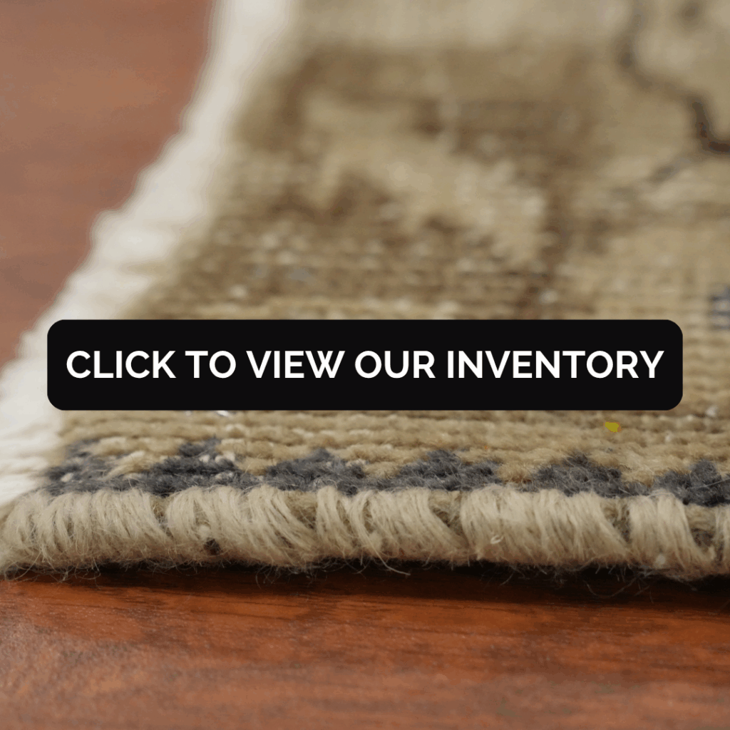 A close-up side view of a rug’s edge, showing its thick woolen weave in beige and gray tones. Text overlay reads “Click to view our inventory.”