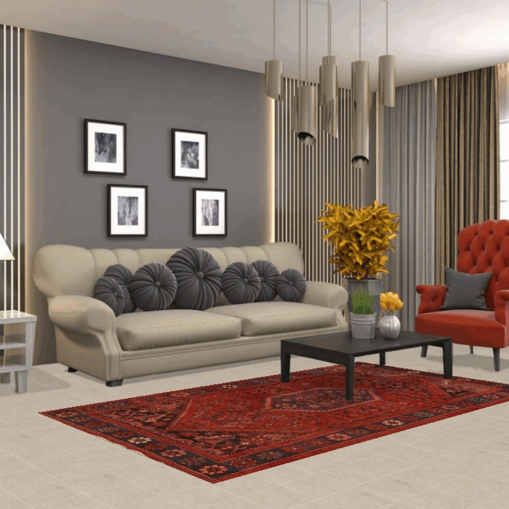 A stylish living room with a gray accent wall, beige sofa with round gray pillows, and an orange armchair. A red patterned area rug adds warmth beneath a black coffee table and modern pendant lights.