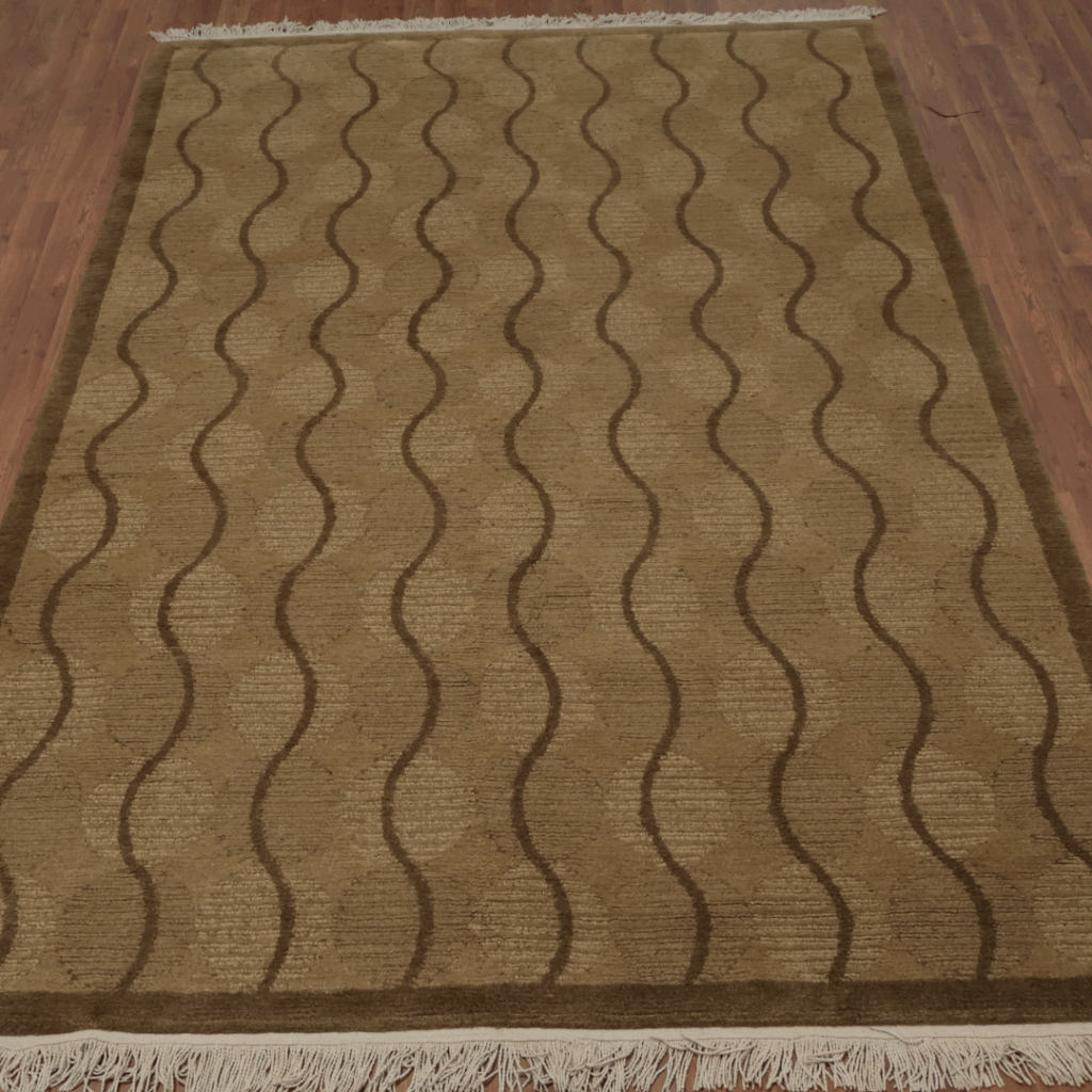 A brown rug with wavy line patterns in varying shades of tan and beige, bordered with fringe on wooden flooring.