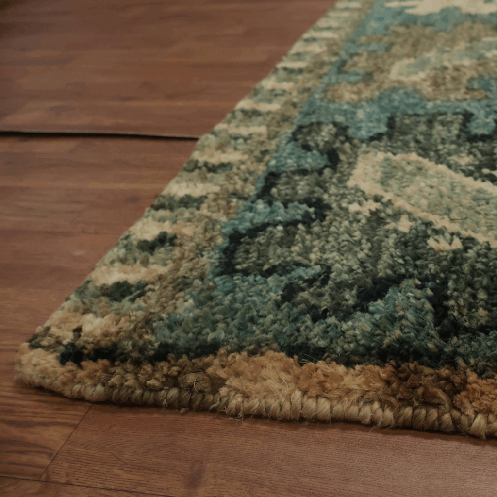 A close-up of a thick, textured rug in shades of green, brown, and cream, showing its plush pile and weave detail.